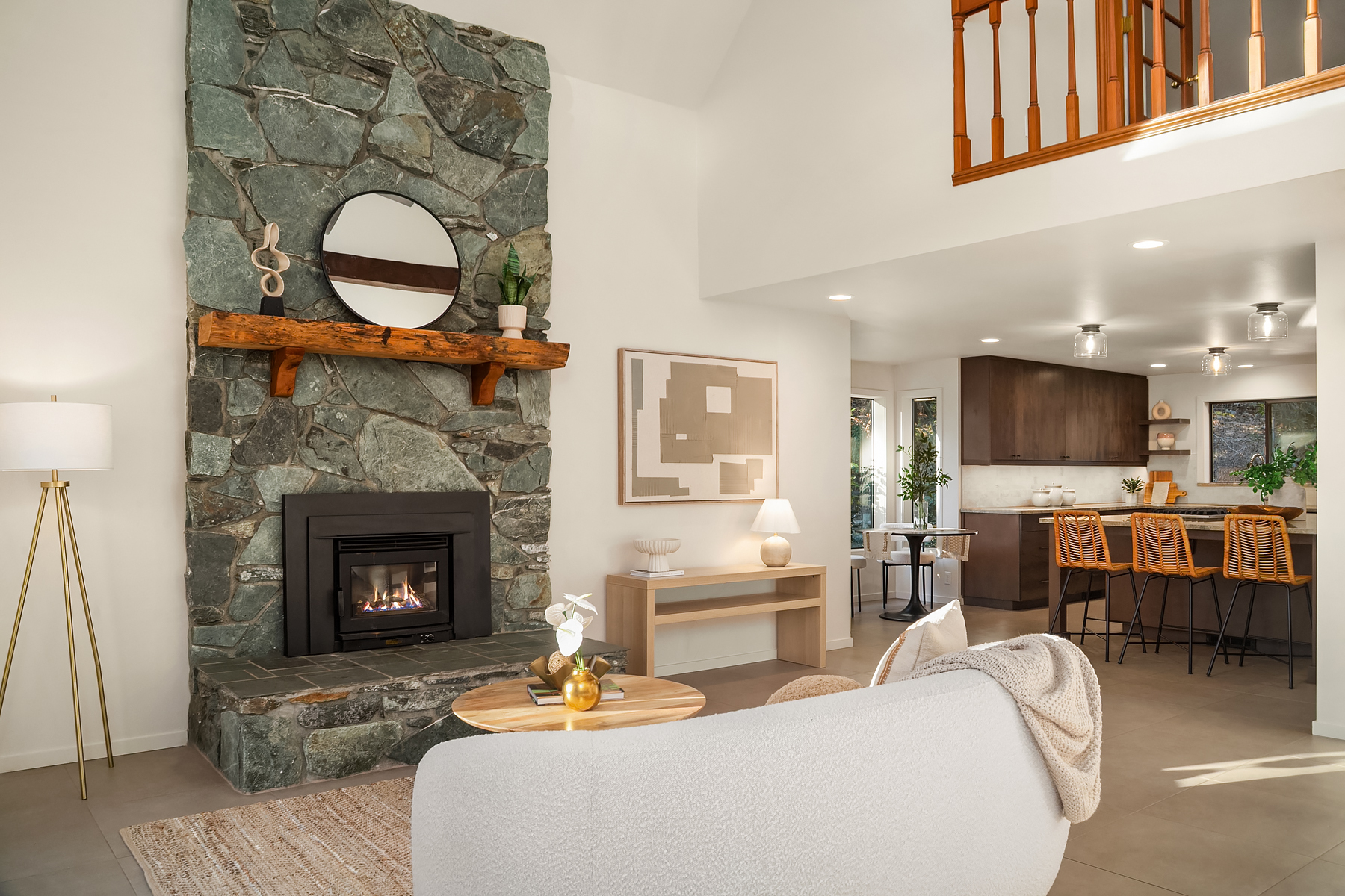 The green-stone hearth, honey-wood mantle, and walnut kitchen beyond